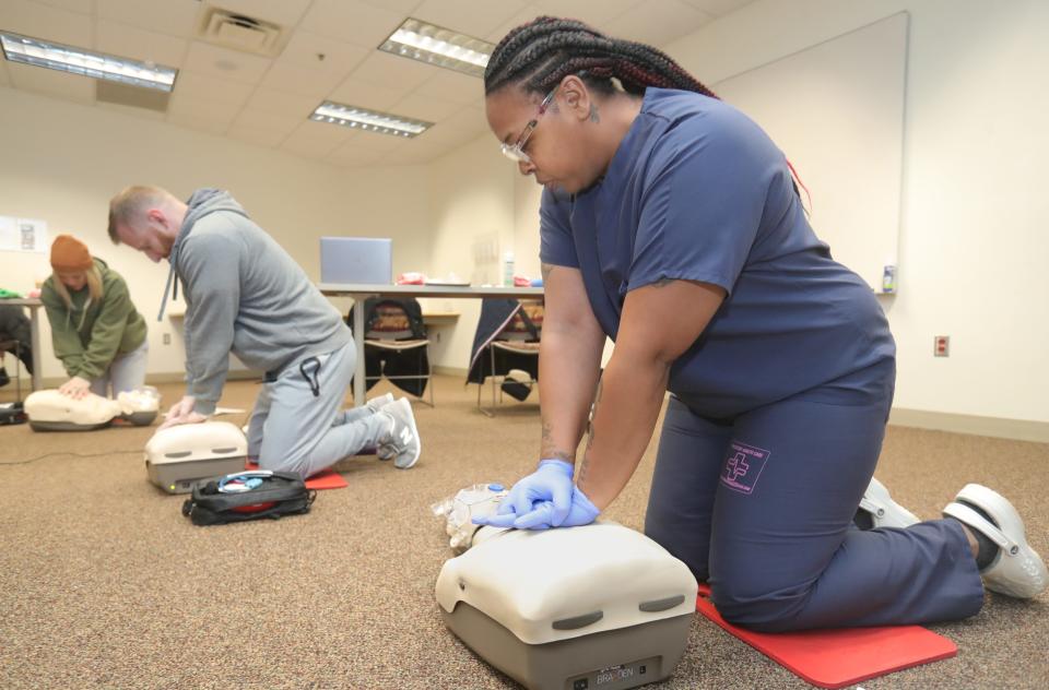 Libby Pruitt of Stow, left, Benjamin Turney of Cleveland, and Toccara Varner of Akron, right, perform chest compressions during a CPR class Wednesday at the Summit County Red Cross in Akron.