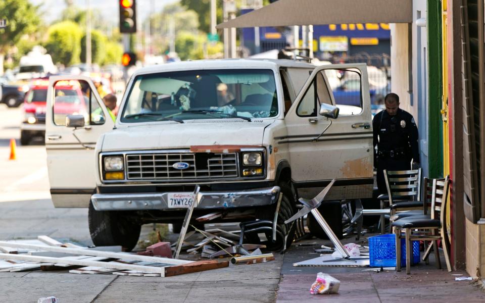 An official looks into a van that plowed into a group of people on a Los Angeles pavement - Credit: AP