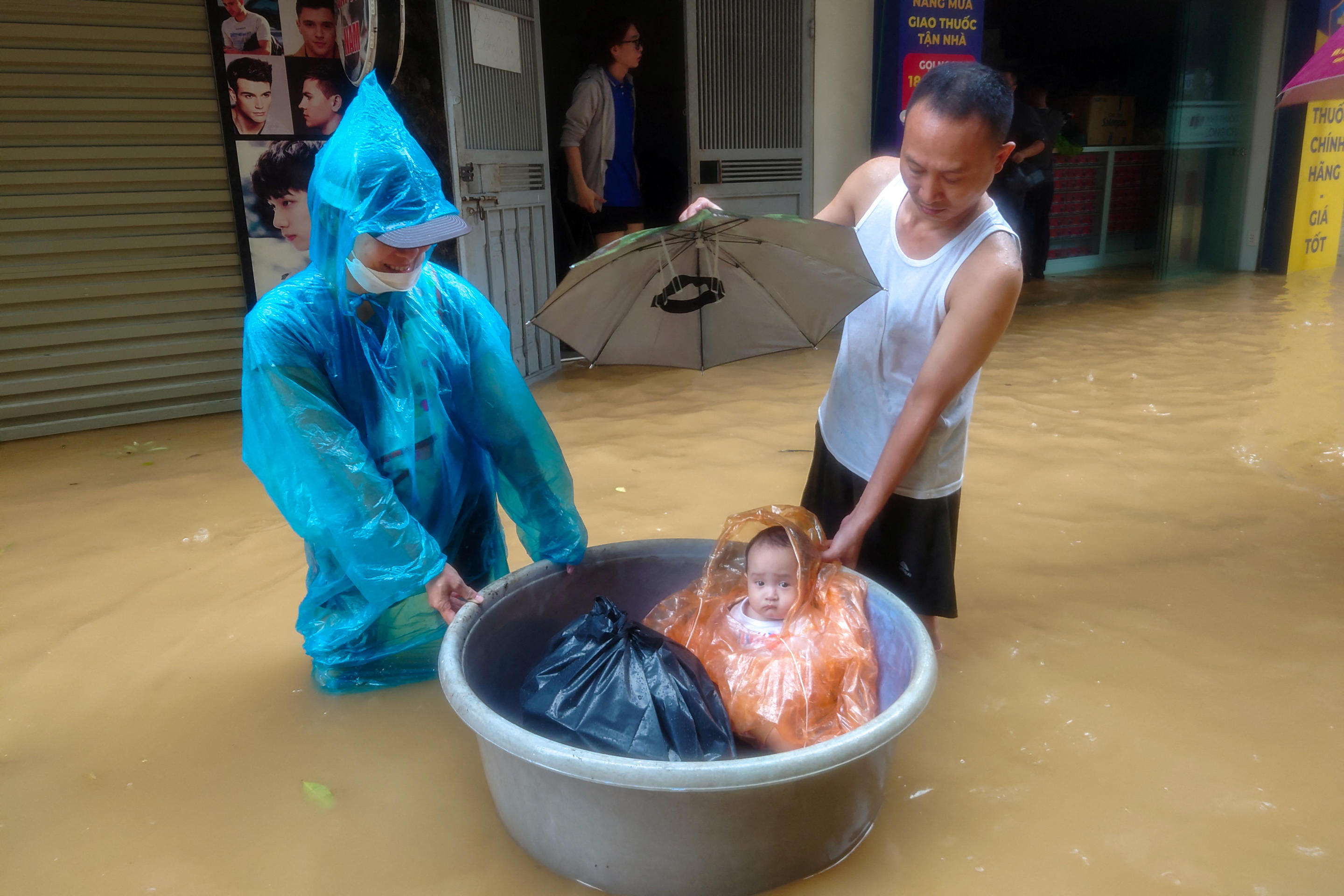 A boy sits in a floating basket as people wade through a flooded street following the impact of Typhoon Yagi, in Hanoi, Vietnam, September 11, 2024. (Khanh Vu/Reuters)