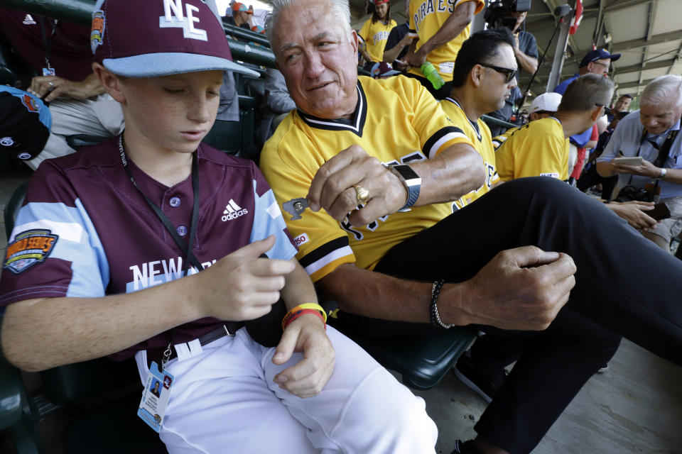 FILE - In this Aug. 18, 2019, file photo, Pittsburgh Pirates' Clint Hurdle, right, hands a commemorative pin to Barrington, Rhode Island player Owen Pfeffer in the stands at Lamade Stadium as they watched a baseball game at the Little League World Series tournament in South Williamsport, Pa. A major league player for 10 years and a manager for 17 more before getting fired by the Pittsburgh Pirates last September, Hurdle was known throughout baseball for his positive approach _ with a big personality and frame to match. (AP Photo/Gene J. Puskar, File