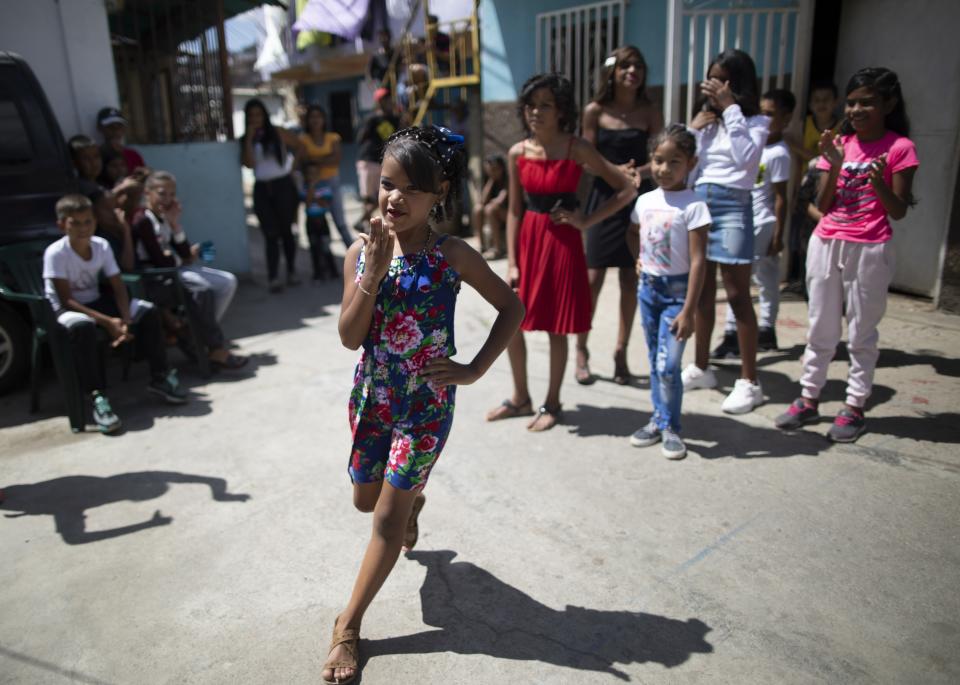 Contestant Yangervis Blanco, 7, blow kisses as she walks past a 3-judge panel during a homespun beauty pageant in the Antimano neighborhood of Caracas, Venezuela, Friday, Feb. 5, 2021. Neighbors in the hillside barrio gathered for the carnival pageant tradition to select their child queen for the upcoming festivities. (AP Photo/Ariana Cubillos)