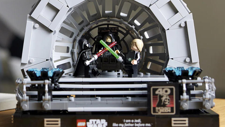 A closeup of Luke and Darth Vader minifigures locked in combat in front of the Emperor