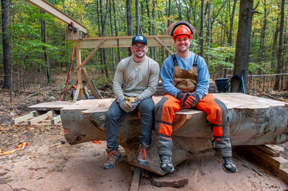 Matt Cuneo, left, and Kevin Merle sit on the trunk of a large beech tree that stood in the heart of downtown Ashland for nearly 200 years.