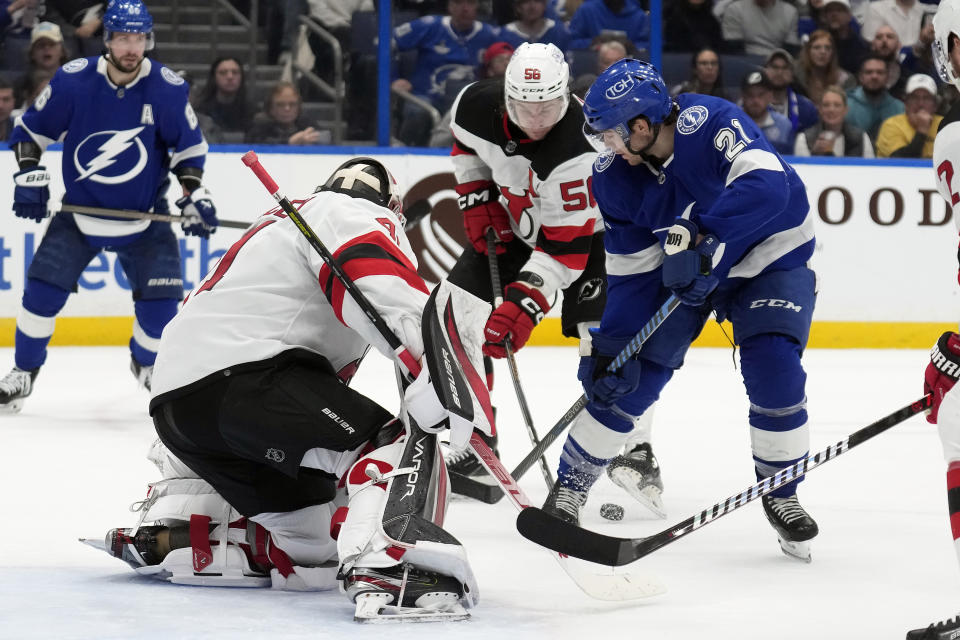 Tampa Bay Lightning center Brayden Point (21) and New Jersey Devils left wing Erik Haula (56) battle for a loose puck in front of goaltender Vitek Vanecek (41) during the second period of an NHL hockey game Thursday, Jan. 11, 2024, in Tampa, Fla. (AP Photo/Chris O'Meara)