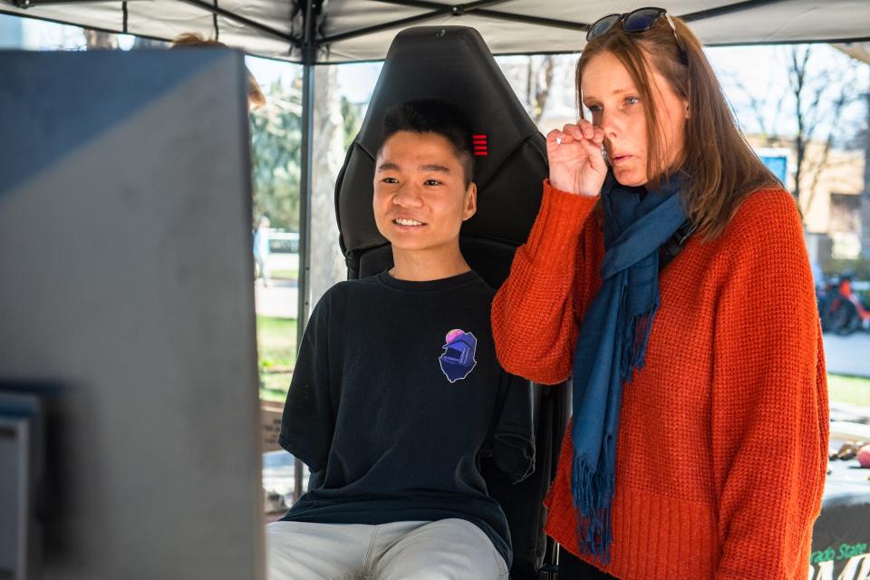 Heather Zoccali wipes away a tear as Colorado State student Jian Cohen drives a car racing simulator during an "Engineering Day," where senior undergraduate students showcase projects, on campus on Monday. A team of students designed a vehicle control system that Cohen, who was born without arms, can steer with his feet. Cohen is good friends with Zoccali's son, who was paralyzed in a 2015 hit-and-run crash.
