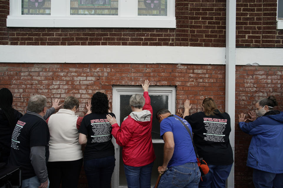 People pray as they hold their hands on a prayer wall outside of the historic Vernon African Methodist Episcopal Church in the Greenwood neighborhood during the centennial of the Tulsa Race Massacre, Monday, May 31, 2021, in Tulsa, Okla. The church was largely destroyed when a white mob descended on the prosperous Black neighborhood in 1921, burning, killing, looting and leveling a 35-square-block area. (AP Photo/John Locher)