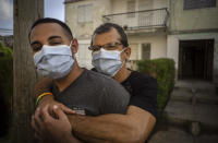 Lázaro “Lachi” González, behind, hugs his partner Adiel González after a video interview outside their home in Matanzas, Cuba, Thursday, Oct. 7, 2021. The socialist government recently published a draft Family Law and asked for public comment ahead of a referendum on legalizing same-sex marriage, as well as expanding grandparents rights, allowing for prenuptial agreements and in cases of divorce, create financial consequences for those who have committed gender violence, amid a total of 480 articles. (AP Photo/Ramon Espinosa)