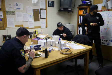 Paradise Police Department officer Tanner Ramlow (L) and Yuba City Police Department officers Nick Morawcznski and Charn Singh (R) eat plates of Thanksgiving dinner brought by chef Jose Andres at the Paradise Police Department in Paradise, California, U.S. November 22, 2018. REUTERS/Elijah Nouvelage