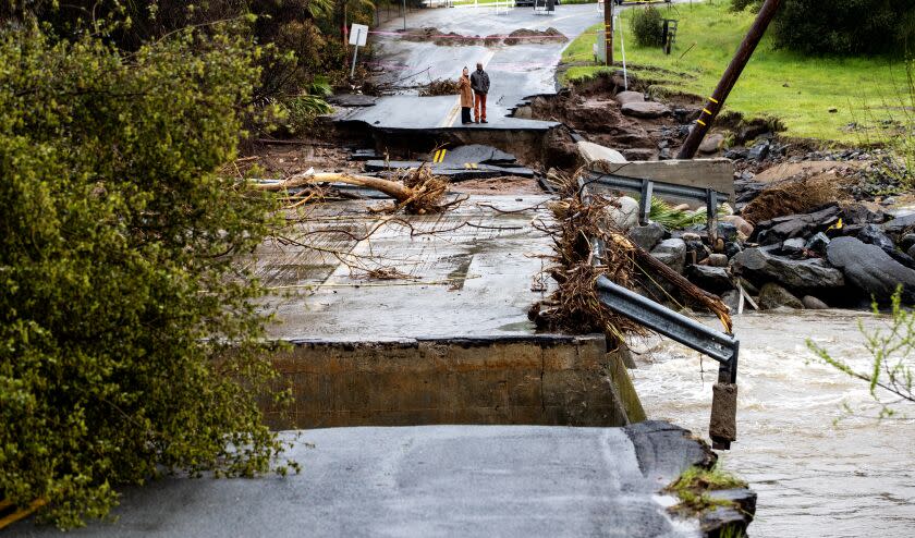 Residents checkout the damage after the fast moving and swollen Tule River crumbled parts of Globe Drive