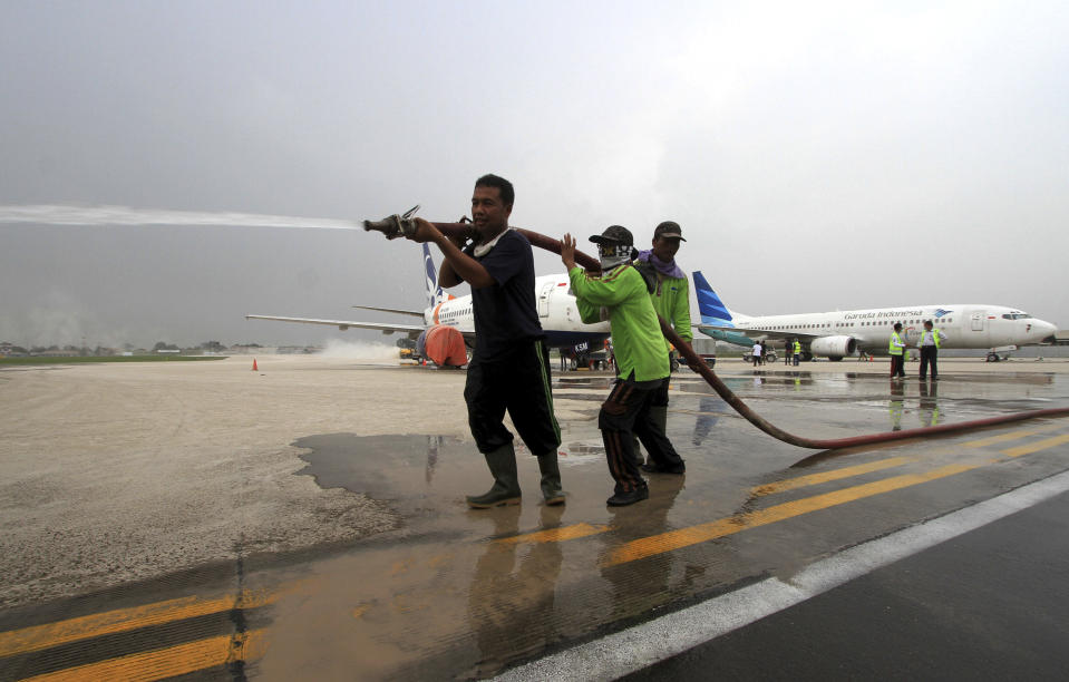 Workers clean the tarmac which was covered with volcanic ash following an eruption of Mount Kelud at Adi Sumarmo airport in Solo, Central Java, Indonesia, Saturday, Feb. 15, 2014. The powerful volcanic eruption on Indonesia's most populous island blasted ash and debris 18 kilometers (12 miles) into the air Friday, forcing authorities to evacuate more than 100,000 and close seven airports. (AP Photo)