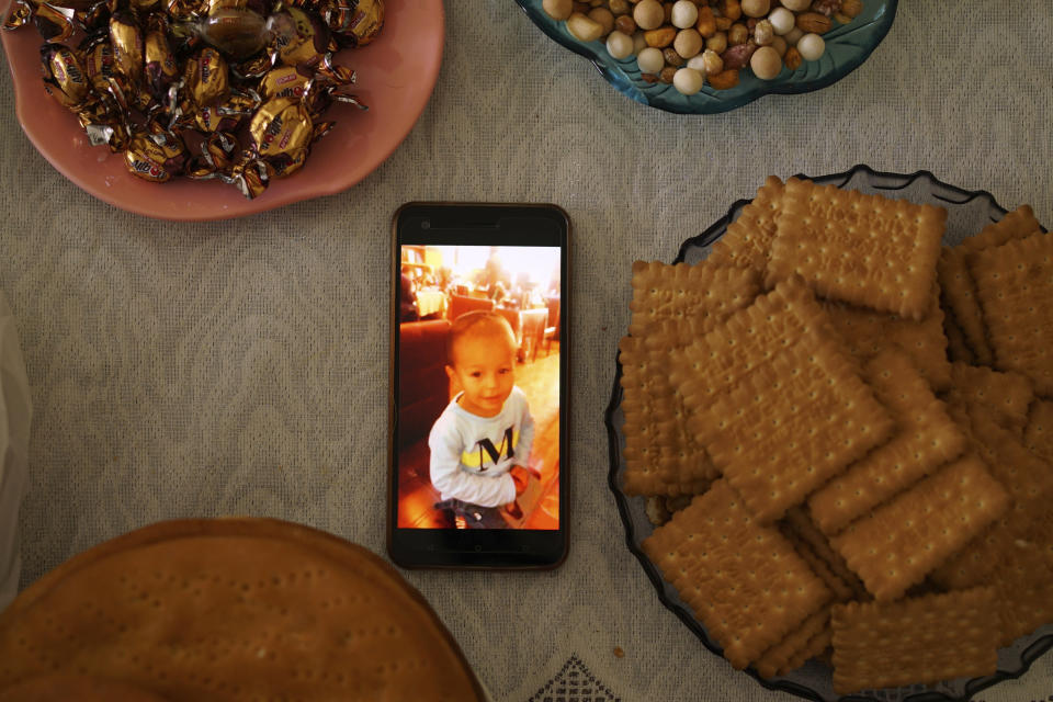 In this Aug. 23, 2018, photo, a phone displaying an image of one of Aziz's children, now missing, sits on a table surrounded by baked goods at his home in Istanbul, Turkey. Aziz, 37, was a surgeon in Hotan, China, before fleeing immediately after receiving a call from the police, leaving his wife and four children behind. The last thing he heard before losing contact with his family in mid-2017 was that his wife was sent to reeducation and three of his children were missing. (AP Photo/Dake Kang)