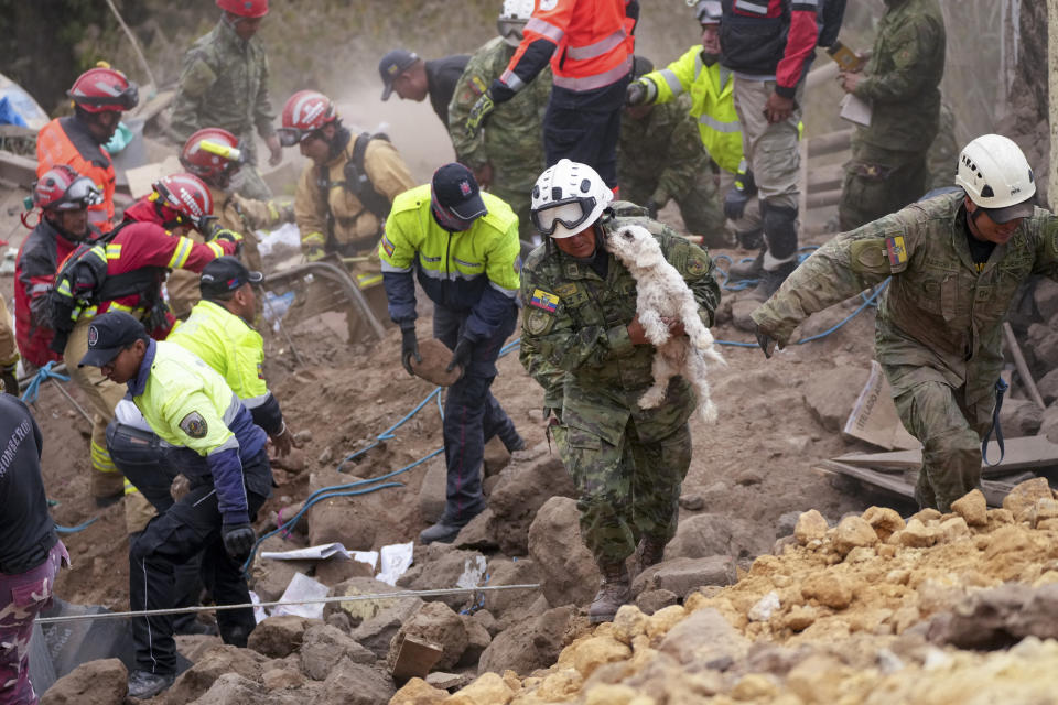 A soldier carries a dog found among the rubble of buildings destroyed by a deadly landslide that buried dozens of homes in Alausi, Ecuador, Monday, March 27, 2023. (AP Photo/Dolores Ochoa)
