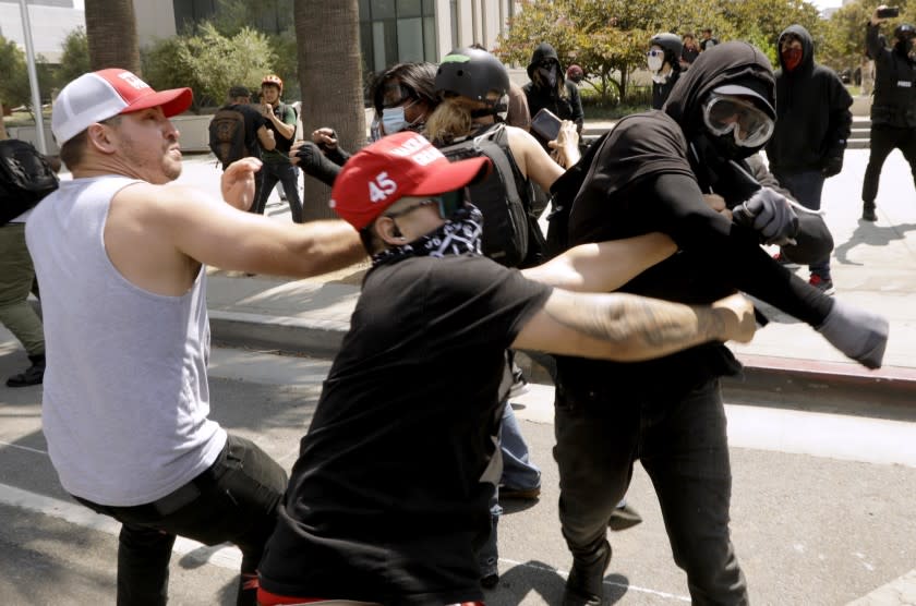 LOS ANGELES, CA - AUGUST 14, 2021 - - Advocates against vaccine mandates, left, confront pro-vaccine advocates in front of the L.A.P.D. Headquarters in downtown Los Angeles on August 14, 2021. One man was stabbed during the melee and was taken by paramedics to a nearby hospital. (Genaro Molina / Los Angeles Times)