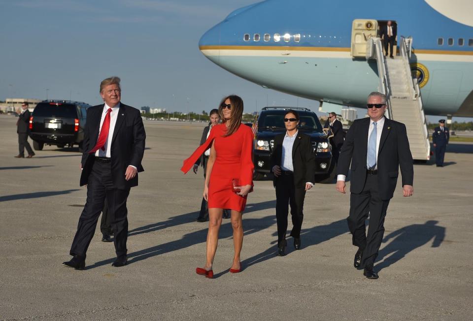 <p>The first lady matched her $2,095 red Givenchy cape dress with $595 Christian Louboutin flats to greet her husband and well-wishers at the airport. (Photo: Getty Images) </p>