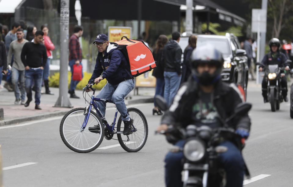 Venezuelan bicycle courier Luis Tarre, 60, takes an order to a customer in Bogota, Colombia, Wednesday, July 17, 2019. Tarre ran his own construction company in his home state of Portuguesa in Venezuela, but after business took a sharp downturn, he moved to Colombia with his family, and has had stints working as a building administrator, a waiter, and a construction assistant. (AP Photo/Fernando Vergara)