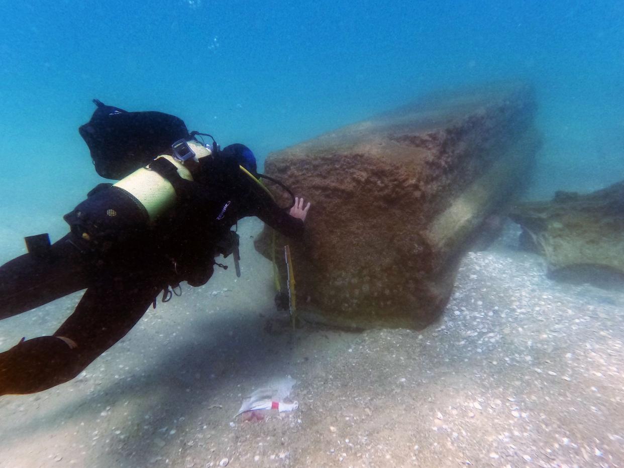 A diver touches an 1,800-year-old beam that sank with a ship in waters off Israel.