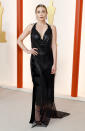 <p>Elizabeth Olsen wears a shimmery draped halter-neck gown with fringe and a sheer overlay at the hem, with ankle-strap heels, fringe earrings and an orange-red lip.</p>
