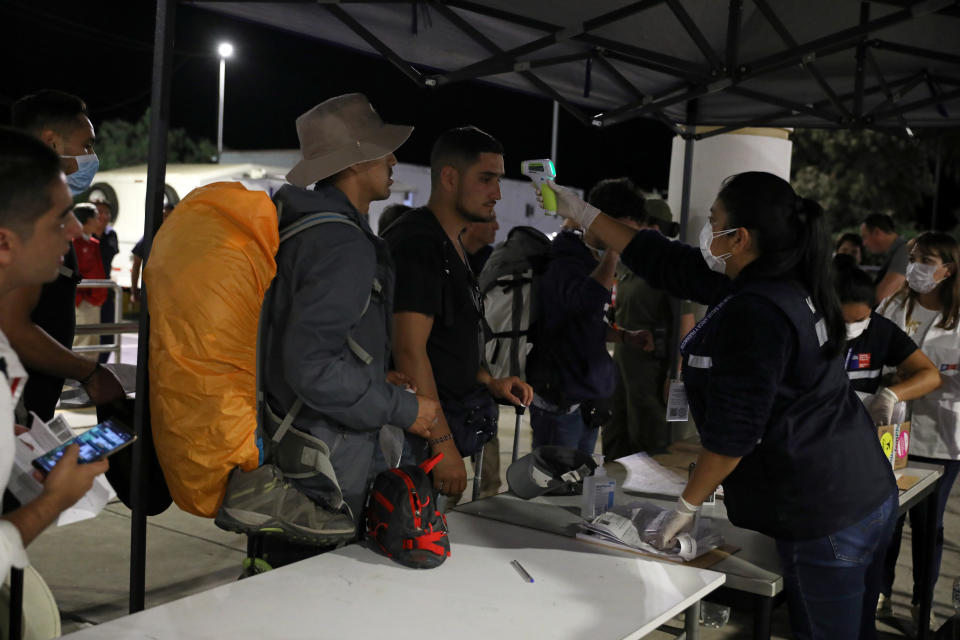 A custom worker checks person's temperature at the border between Chile and Peru, after Chile's government's announcement of the border closure in a bid to slow the spread of coronavirus disease (COVID-19), at Chacalluta check point, Arica