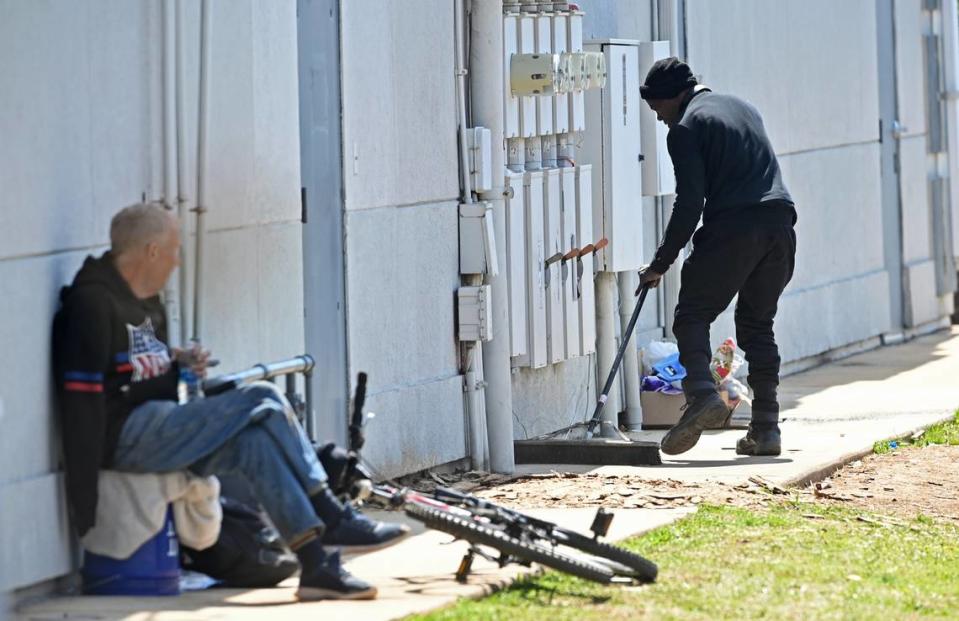 Kenny cleans the area behind a small row of businesses lining South Boulevard near Woodlawn Road area as Lefty Jacobson looks on.