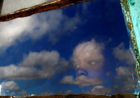 FILE PHOTO: Anda, a local boy, looks out from his hut's window at the burial ground of late former South African President Nelson Mandela ahead of his funeral in Qunu, December 15, 2013. REUTERS/Yannis Behrakis/File photo