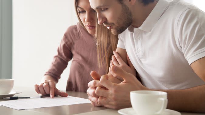 Serious couple studying contract agreement, reading terms and conditions attentively before signing, husband and wife calculating domestic bills, considering mortgage loan offer, health insurance.