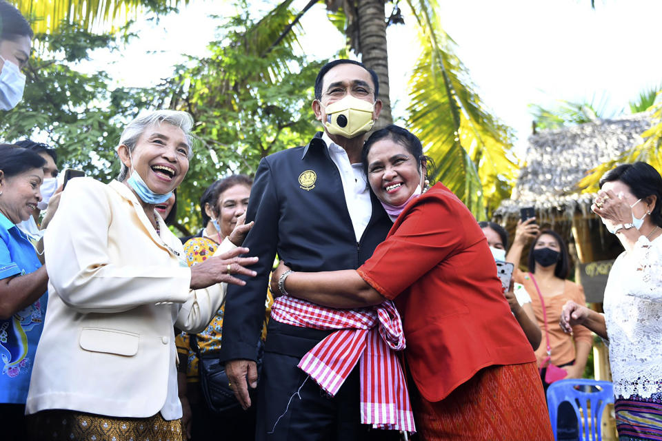 In this photo released by Government Spokesman Office, a well-wisher hugs Thailand's Prime Minister Prayuth Chan-ocha in Samut Songkhram province, Thailand, Wednesday, Dec. 2, 2020. Thailand’s highest court Wednesday, has acquitted Prayuth of breaching ethics clauses in the country’s constitution, allowing him to stay in his job. (Government Spokesman Office via AP)