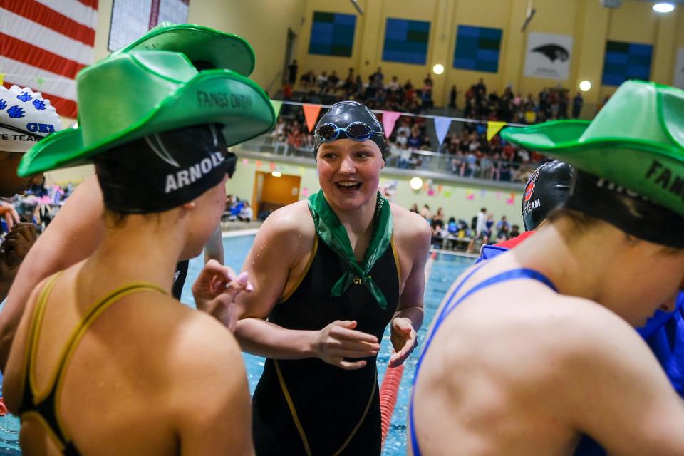 Fossil Ridge’s Ella Gaca-Thiele, center, laughs with teammates before a race at the Colorado 5A girls swimming state championships on Friday, Feb. 9, at Veterans Memorial Aquatics Center in Thornton.