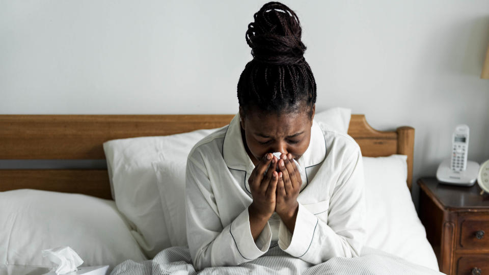 A woman sneezing in bed with allergies