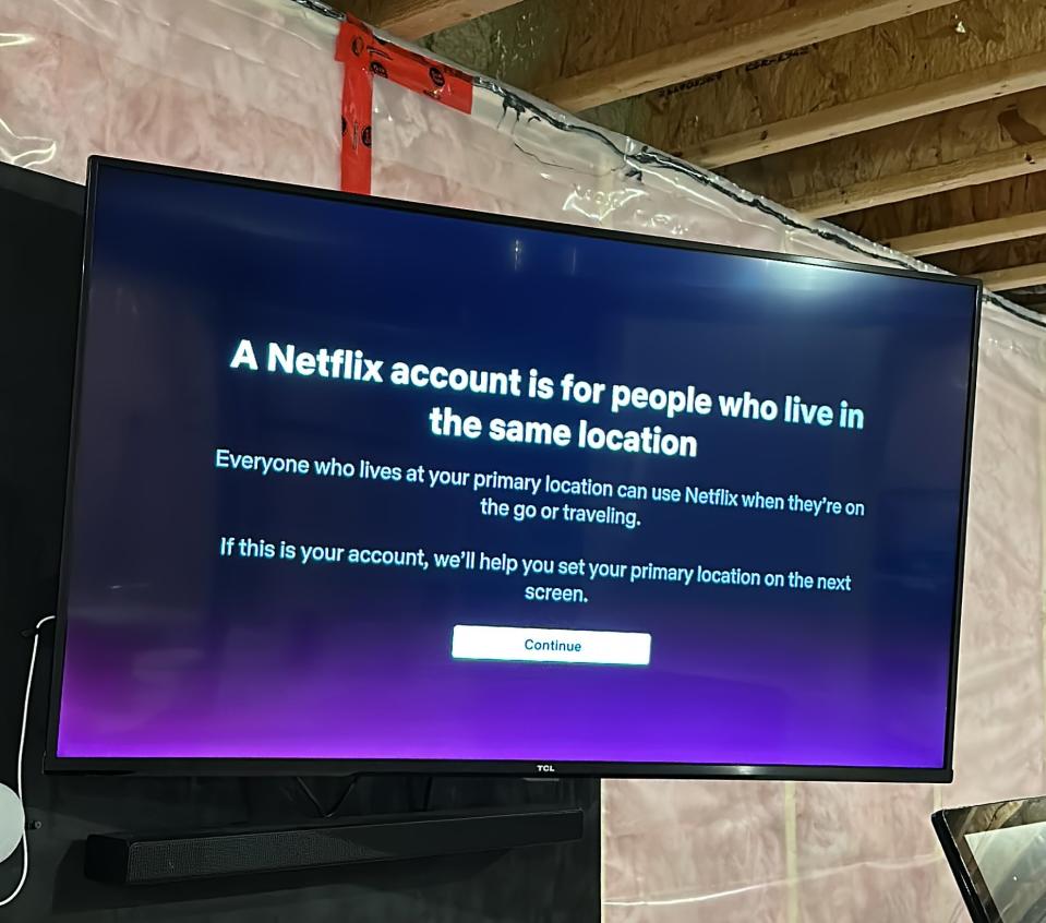 A TV mounted on a wall with the Netflix password crackdown message: 