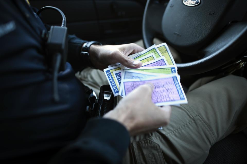 In this Friday, Dec. 13, 2013 photo, Homeless Liaison Officer Tom Gentner sorts through paper phone messages he picked up from the police station while sitting in his patrol car during a visit to a camp under the Truman Parkway in Savannah, Ga. Gentner has had no more budget than a typical patrol officer who rides a beat, but after being awarded by the department for his work with the homeless, he will be assigned a new SUV to help him get to remote locations. (AP Photo/Stephen B. Morton)