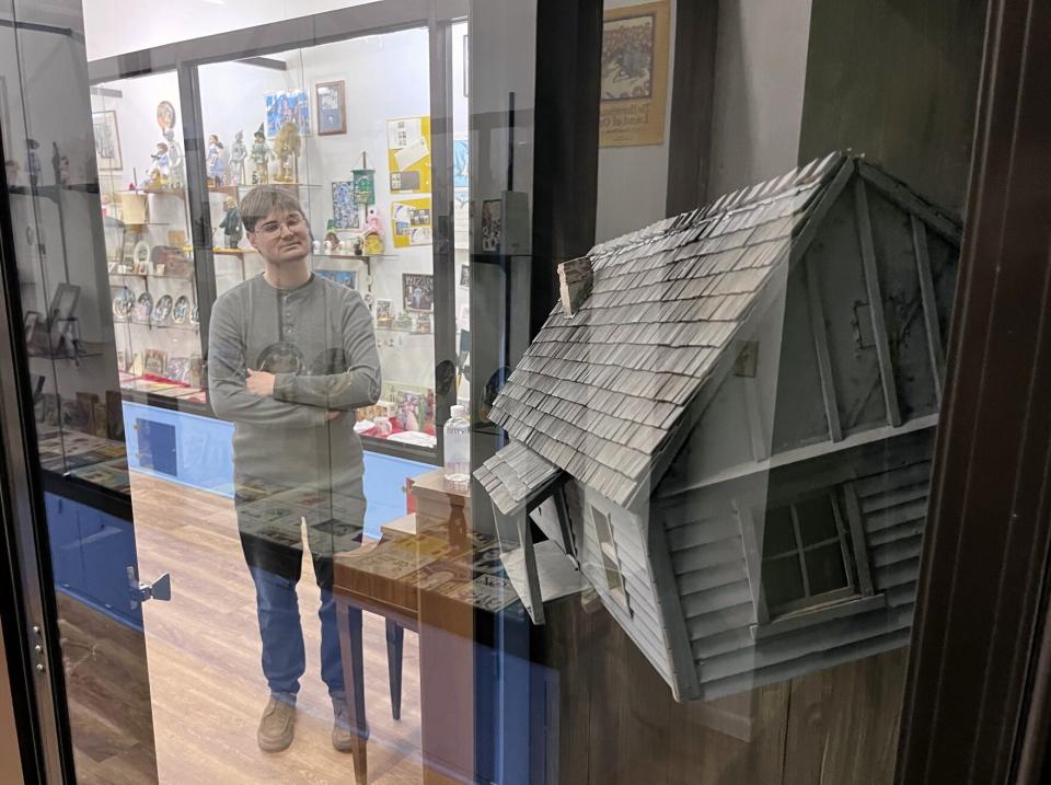 Museum director Nathan Dowell stands next to the actual prop house seen twisting in a tornado in the 1939 film as it hangs suspended in a glass case at the Land of Oz museum in Liberal.