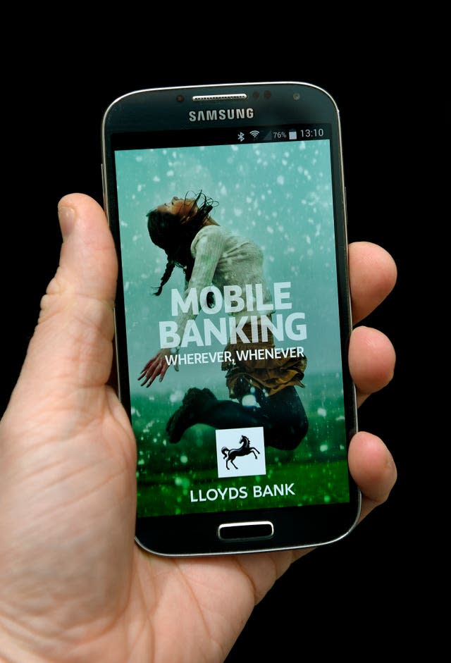 A hand holds a mobile device showing the Lloyds Bank app