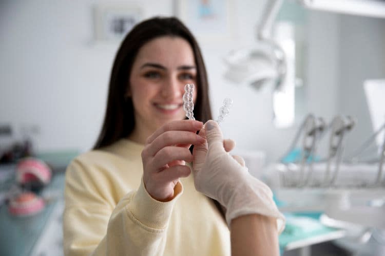 Un dentista dando a una paciente un alineador dental transparente