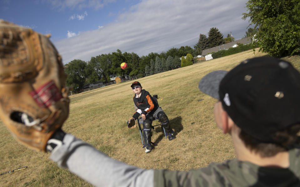 Brady Hill, 14, throws a pitch to his brother Monte, 8, at their home in Meridian, Idaho, June 19, 2023. Brady survived a rare brain cancer as a baby, but requires round the clock care. Families of severely disabled children across the country are worried about the future of crucial Medicaid payments they started receiving to provide care during the COVID-19 pandemic. (AP Photo/Kyle Green)