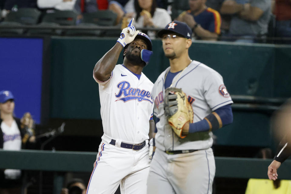 Texas Rangers' Adolis Garcia, left, celebrates his run-scoring single as Houston Astros first baseman Yuli Gurriel, right, looks on during the seventh inning of a baseball game Monday, April 25, 2022, in Arlington, Texas. (AP Photo/Michael Ainsworth)