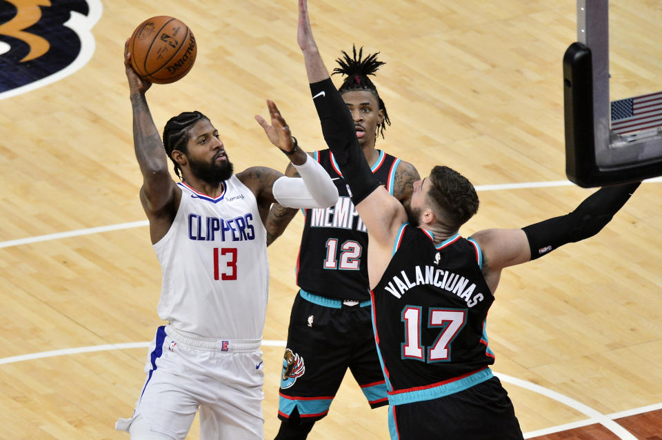 Los Angeles Clippers guard Paul George (13) shoots against Memphis Grizzlies center Jonas Valanciunas (17) and guard Ja Morant (12)in the second half of an NBA basketball game Thursday, Feb. 25, 2021, in Memphis, Tenn. (AP Photo/Brandon Dill)