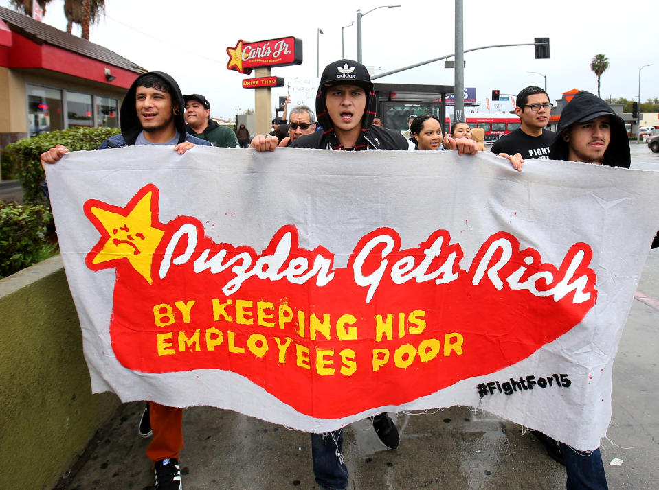 Carl’s Jr. employees hold a sign protesting CKE CEO Andy Puzder, Donald Trump’s nominee for Secretary of Labor.