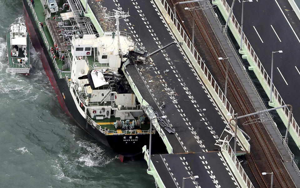 A tanker is seen after it slammed into the side of a bridge connecting the airport to the mainland, damaging part of the bridge and the vessel in Osaka, western Japan, Tuesday, Sept. 4, 2018. A powerful typhoon blew through western Japan on Tuesday, causing heavy rain to flood the region's main offshore international airport and high winds to blow a tanker into a connecting bridge, disrupting land and air travel. (Kentaro Ikushima/Mainichi Newspaper via AP)