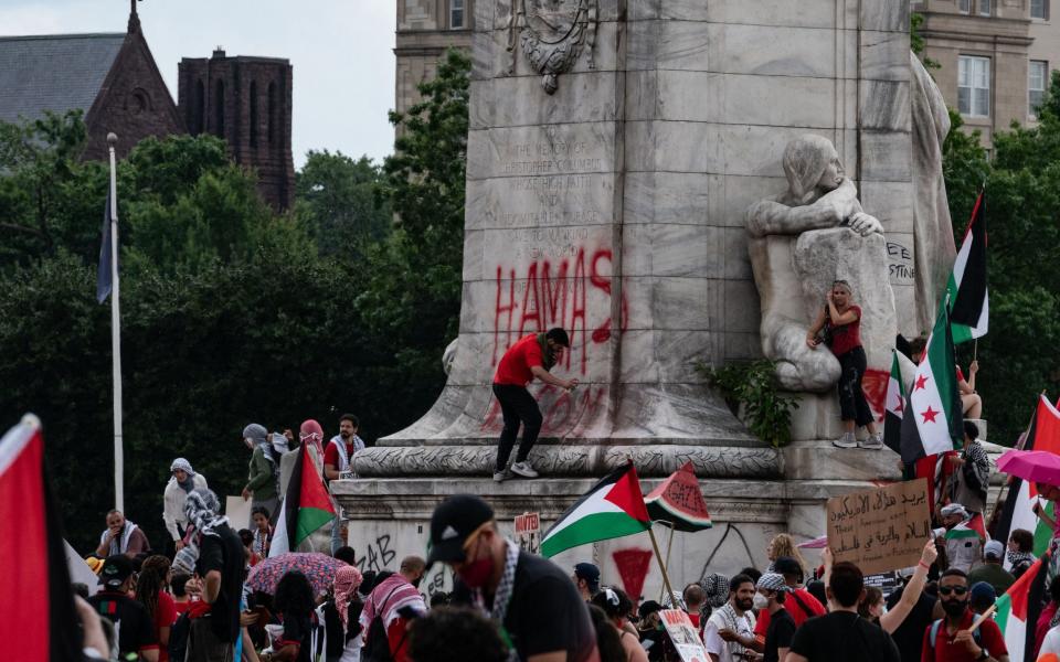 Protestor spray paints on the base of the Christopher Columbus Memorial Fountain