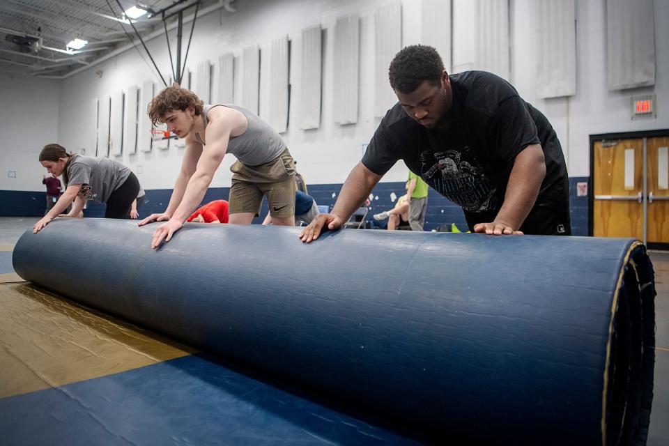 Roberson wrestlers, from left, Lilly Reese, Henry Stubblefield, and Itachi Duvernay, roll up a wrestling mat after practice, February 13, 2024.