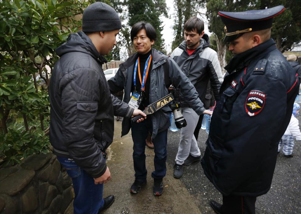 Russian police perform security checks on a journalist at the entrance of church during Orthodox Epiphany celebrations in Sochi January 19, 2014. REUTERS/Alexander Demianchuk (RUSSIA - Tags: SPORT OLYMPICS MILITARY RELIGION)