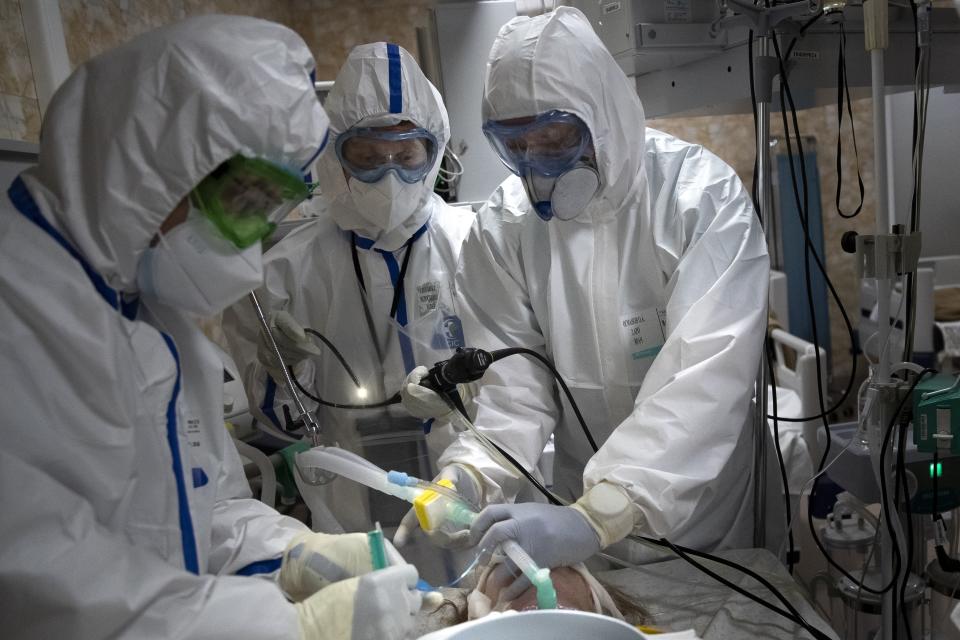 In this photo taken on Friday, May 15, 2020, Dr. Osman Osmanov, right, and Dr. Konstantin Glebov, center left, and Dr. Vitaly Mushkin perform tracheal intubation of a coronavirus patient on artificial lung respiration at an intensive care unit of the Filatov City Clinical Hospital in Moscow, Russia. Moscow accounts for about half of all of Russia's coronavirus cases, a deluge that strains the city's hospitals and has forced Osmanov to to work every day for the past two months, sometimes for 24 hours in a row. (AP Photo/Pavel Golovkin)