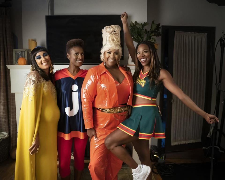 the four women posing in Cleopatra, jigaboo, Nisi, and Clover Cheerleader costumes.