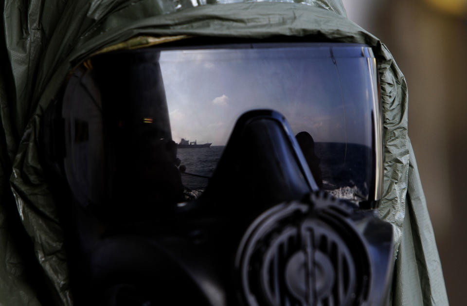 A crew member of the Danish warship Esbern Snare wears a protective mask which shows the reflection of the Danish cargo ship Ark Futura, during emergency drills on the sea between Cyprus and Syria, Sunday, Jan. 5, 2014. Two cargo ships and their warship escorts set sail at waters near Syria where they will wait for orders on when they can head to the Syrian port of Latakia to pick up more than 1,000 tons of chemical agents. (AP Photo/Petros Karadjias)