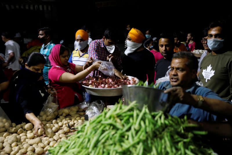 People buy vegetables at a market after India's Prime Minister Narendra Modi called for a nationwide lockdown starting midnight to limit the spreading of coronavirus disease (COVID-19), in New Delhi