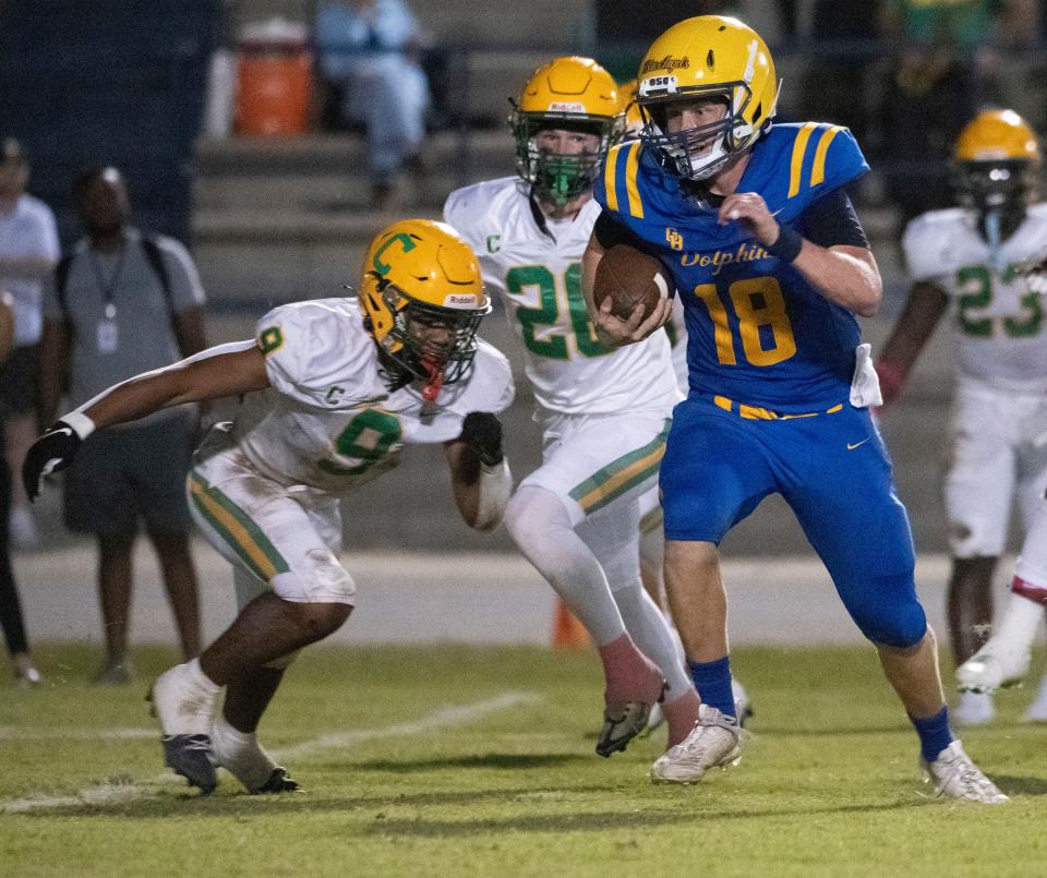 During Friday's high school football matchup, Gulf Breeze quarterback Battle Alberson (No. 18) gets flushed out of the pocket by Catholic's Justin Weatherall (No. 9).