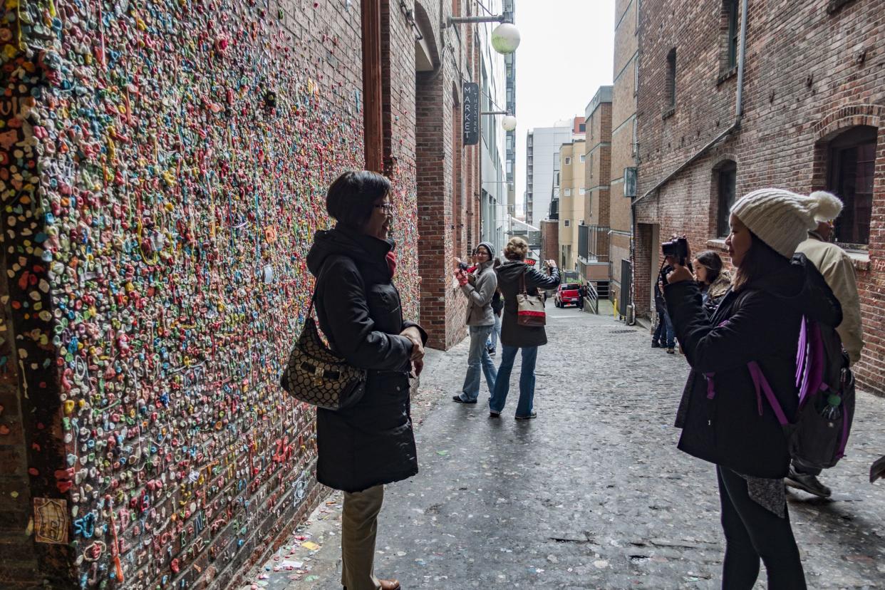 Seattle, Washington/USA - December 24, 2015: Tourists Admiring and Take Photo Selfies in Front of the Gum Wall in Post Alley at Pike Place Market. This is a Very Popular Famous Landmark Attraction in Seattle, WA.