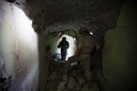 In this photo taken on Wednesday, Sept. 25, 2019, Russian military work inside caves that served as a major rebel base outside Latamna near the Syrian town of Khan Sheikhoun, Syria. The caves were dug by the rebels who controlled the area until it was captured by Syrian government troops last month. (AP Photo/Alexander Zemlianichenko)