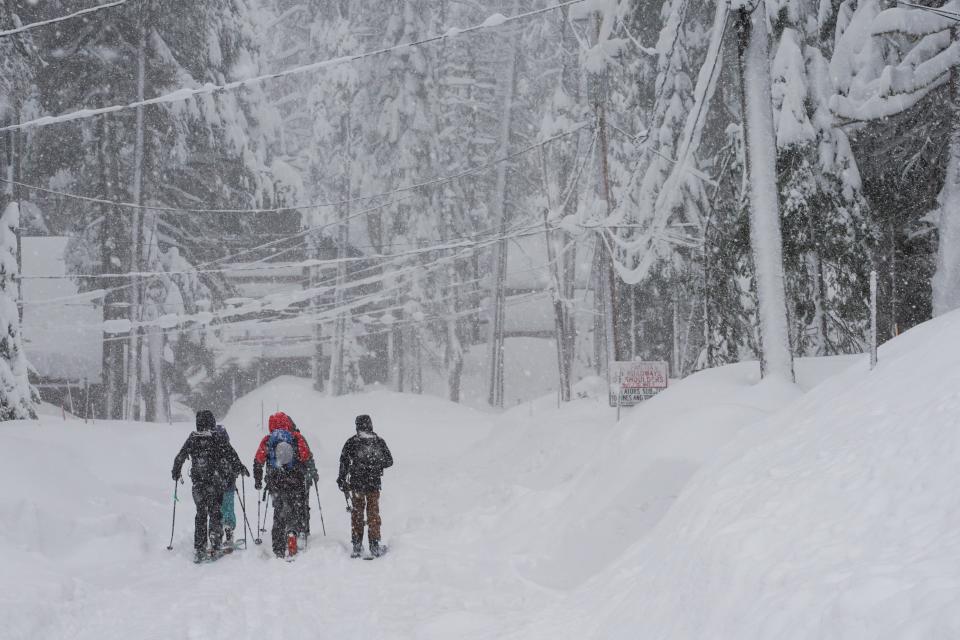 A group of friends sky on a residential street during a storm, Saturday, March 2, 2024, in Truckee, Calif.