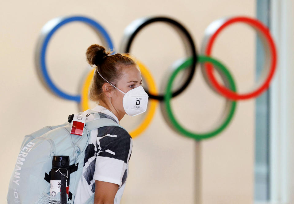 A German athlete, wearing face mask, walks past the Olympic rings display on their arrival at Haneda airport in Tokyo, Thursday, July 1, 2021. The pressure of hosting an Olympics during a still-active pandemic is beginning to show in Japan. The games begin July 23, with organizers determined they will go on, even with a reduced number of spectators or possibly none at all.(Kyodo News via AP)